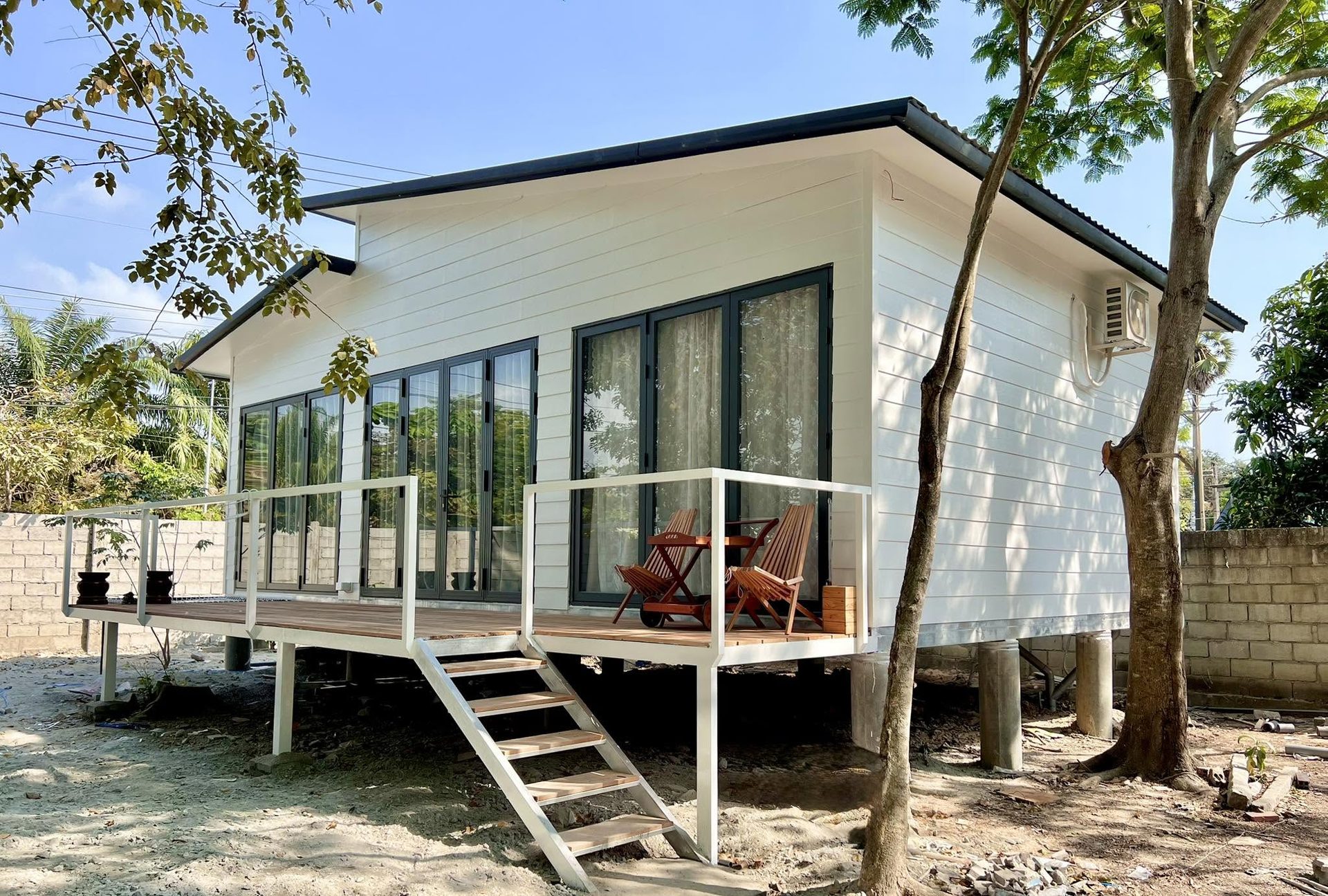 Một căn nhà nhỏ có hiên gỗ giữa vườn cây